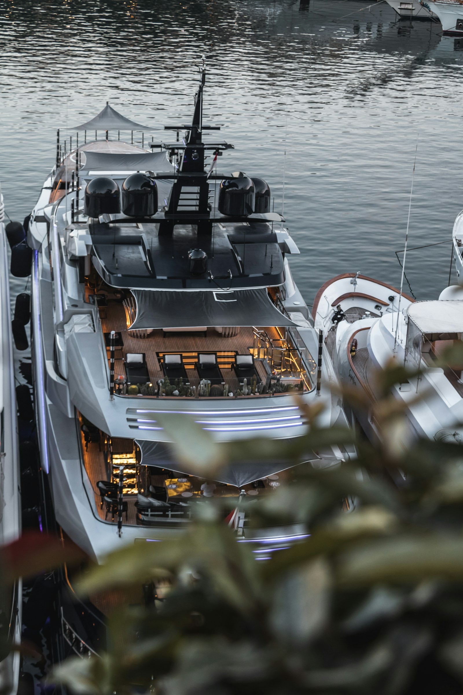 Aft deck of a superyacht lit at dusk in a marina
