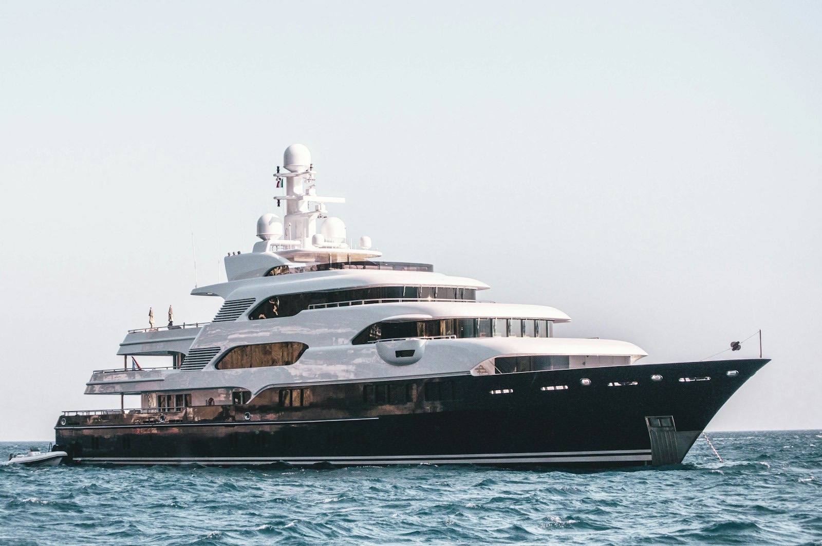 Dark-hulled superyacht at anchor on open water