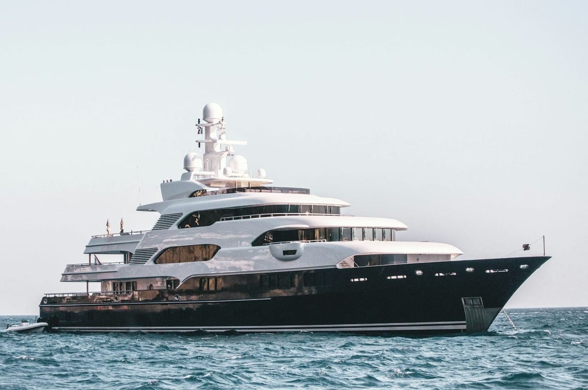 Dark-hulled superyacht at anchor on open water